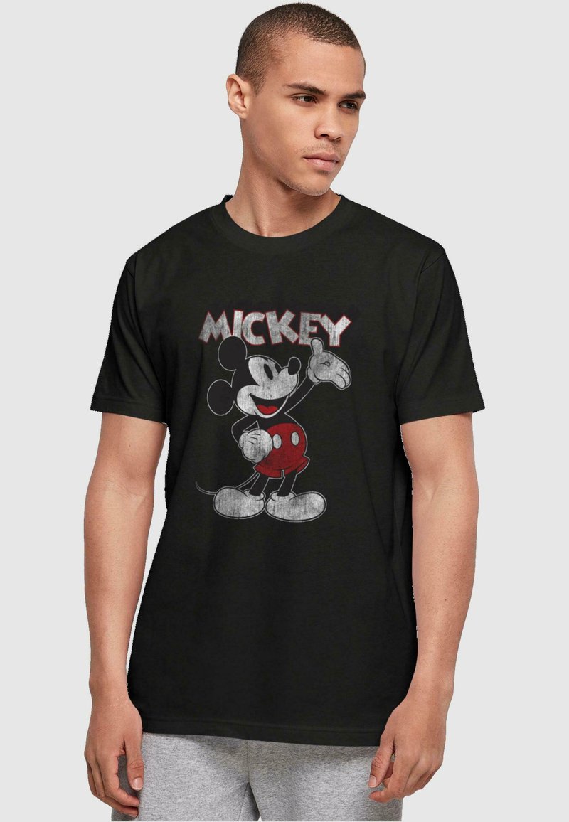 Camiseta de algodón negra con un gráfico de Mickey Mouse en pantalones cortos rojos. El diseño incluye el nombre "MICKEY" en letras estilizadas arriba.