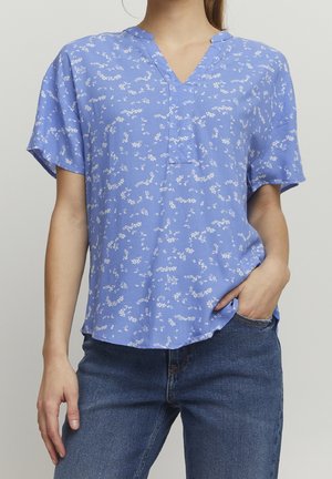 Kortærmet bluse med V-udskæring i lyseblåt stof med hvide blomsterprint. Har en afslappet pasform og en diskret knapstolpe.