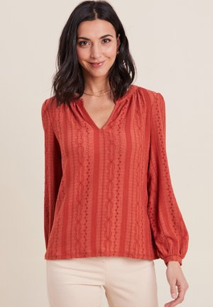 Rode, gestructureerde blouse met een V-hals, lange pofmouwen en verticale strepen. Bevat gedetailleerde patronen en heeft een losse fit.