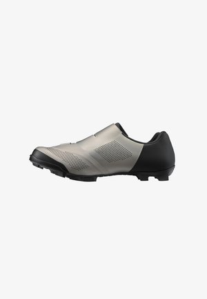 Zapatilla de ciclismo negra y plateada con una parte superior lisa, diseño perforado y una suela resistente para mayor tracción. Cuenta con una forma aerodinámica y acentos mínimos.