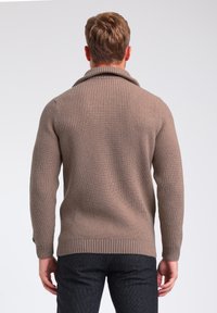 Brauner gerippter Pullover mit großem, umgeschlagenem Kragen, aus gestricktem Material. Hat lange Ärmel und eine taillierte Silhouette. Rückansicht.