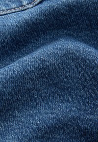 Tessuto denim blu con una texture liscia, un motivo intrecciato distintivo e sottili variazioni di tonalità e tonalità, creando profondità e interesse visivo.