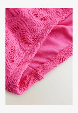 Heldere roze stof met een gestructureerd patroon en lussen, met een gladde afwerking aan de onderzijde. De randen hebben een decoratieve gehaakte rand.