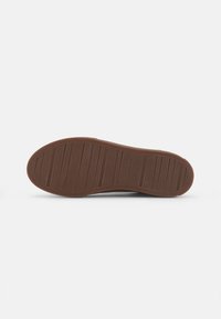 Brown rubber sole with vertical ridges for traction, curved shape, and a smooth surface. Marked with "Vagabond" and size "37."