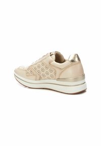 Deportivas de cuero beige con diseño perforado, acentos metálicos dorados, suela blanca y cierre de cordones. Textura suave con cuello acolchado.