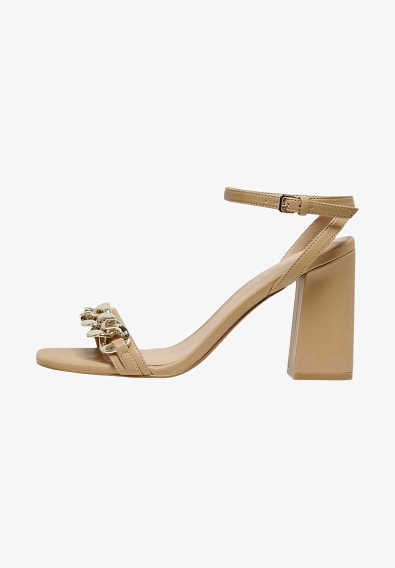 Sandalias de tacón alto beige con un tacón ancho, punta abierta, correa en el tobillo ajustable y detalle metálico dorado en la parte delantera. Textura suave.