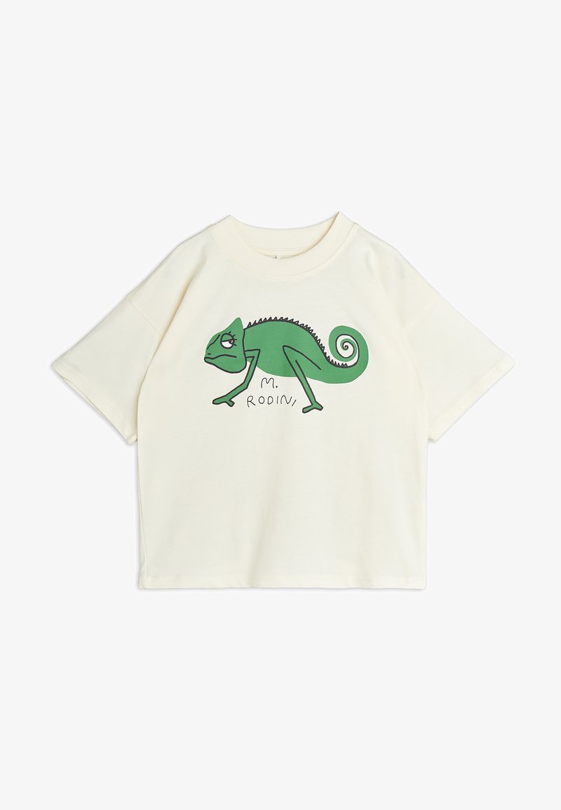 Camiseta de manga corta en color crema con un gráfico de un camaleón verde y texto, hecha de algodón suave, con un corte holgado y escote redondo.