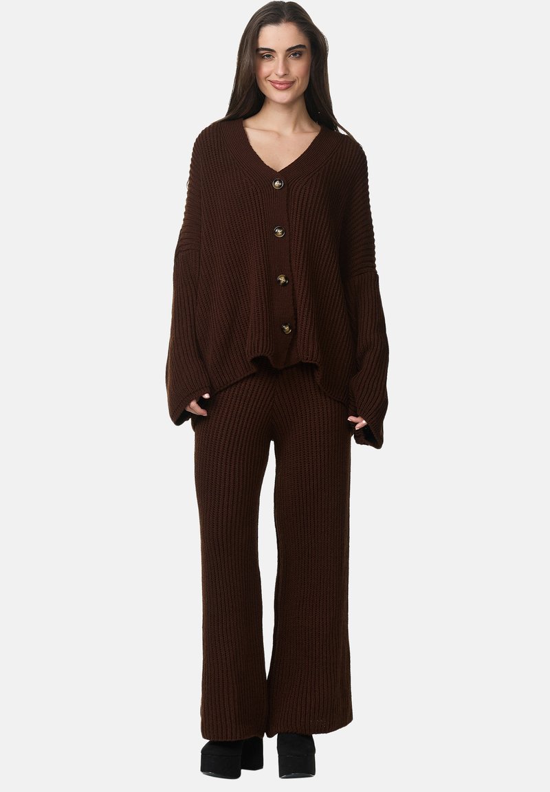 Pull en tricot côtelé marron avec un décolleté en V plongeant et cinq boutons dorés, associé à un pantalon large assorti. Texture épaisse et coupe décontractée.
