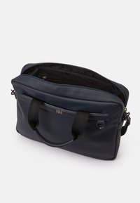 Bolso estructurado en azul marino, fabricado con material texturizado, que cuenta con asas dobles y una abertura con cremallera. El interior incluye bolsillos para una mejor organización.