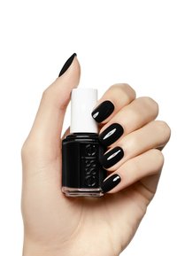 Bouteille de vernis à ongles noir avec un bouchon blanc tenue dans une main. Les ongles sont peints en noir, mettant en valeur une finition brillante. Teint de peau claire de la main visible.