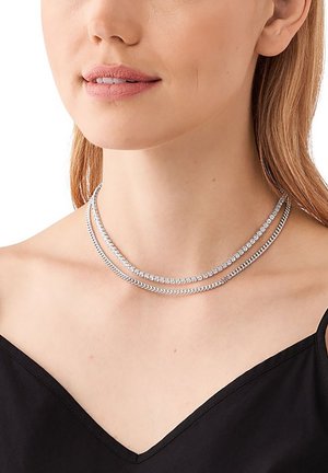 Collana argentata a due strati; uno è una catena liscia, l'altro è decorato con pietre scintillanti, che riposa su un collo nudo.