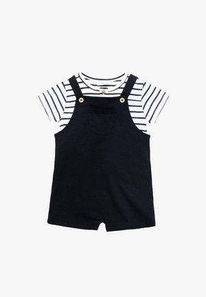 Salopette courte bleu marine avec un t-shirt rayé blanc et bleu marine en dessous. Présente des accents en bois et une poche avant sur la salopette.