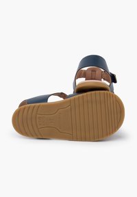 Granatowe sandały dziecięce z otwartym piętą i paskiem wokół kostki. Brązowa wkładka i gumowa podeszwa z rowkami zapewniającymi przyczepność. Rozmiar 24, wyprodukowano w Hiszpanii.