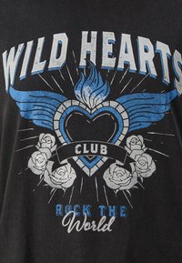 Črni T-majica z grafičnim dizajnom in besedilom "WILD HEARTS CLUB," modrimi plameni, obliko srca in belimi vrtnicami.