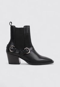 Bottine noire en cuir avec un bout pointu, des panneaux latéraux élastiques et une sangle avec des garnitures en argent. Talon bloc modéré.