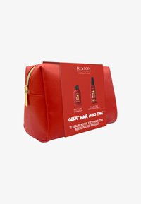 Trousse de maquillage rouge à finition texturée avec une fermeture éclair dorée, présentant une étiquette affichant des bouteilles de shampooing et de traitement capillaire.