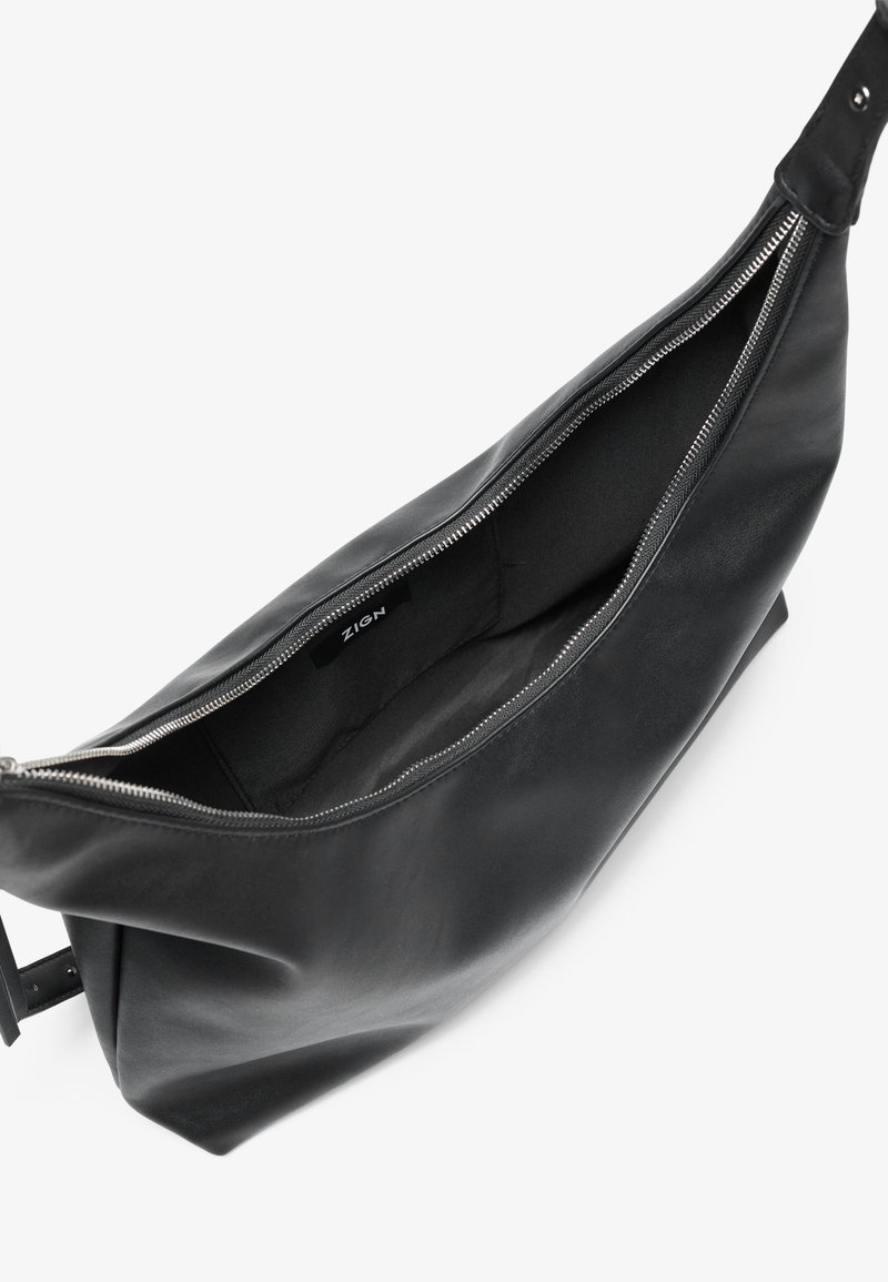 Bolso de cuero negro con una apertura amplia, cierre de cremallera y textura suave. El interior cuenta con un forro oscuro y una etiqueta de marca visible.