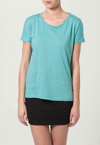 T-shirt a maniche corte di un delicato verde acqua realizzato in tessuto morbido, con scollatura rotonda e vestibilità morbida, abbinato a una gonna nera attillata.