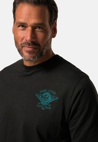 Sort bomulds T-shirt med turkise broderede vinger, med teksten "SAND DUNES STATE PARK", rund halsudskæring og korte ærmer.