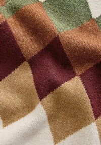 Villasegust sisaldav tekstiil, millel on maapindade tooni ruuduline mustriga: tumepunane, roheline, pruun, kreem, pehme ja tekstuuriga pind.
