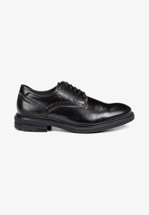 Chaussures habillées en cuir noir avec une finition lisse, un bout arrondi et de subtils détails de brogue. Elles comportent une semelle en caoutchouc noir et un système de laçage.