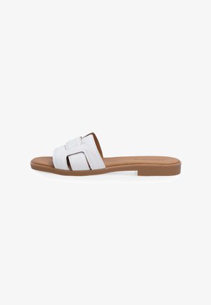 White leather slide sandal with two overlapping straps, flat brown sole, and minimalistic design. Smooth texture with a simple aesthetic.