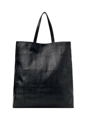 Grand sac cabas en cuir noir avec un design de panneaux cousus et deux fines bretelles, présenté sur fond blanc.
