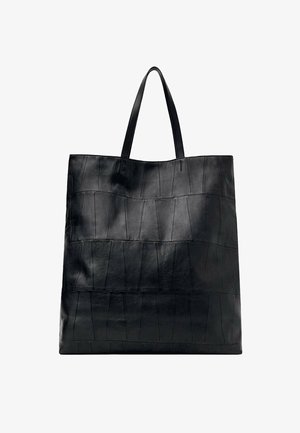Grand sac cabas en cuir noir avec un design de panneaux cousus et deux fines bretelles, présenté sur fond blanc.