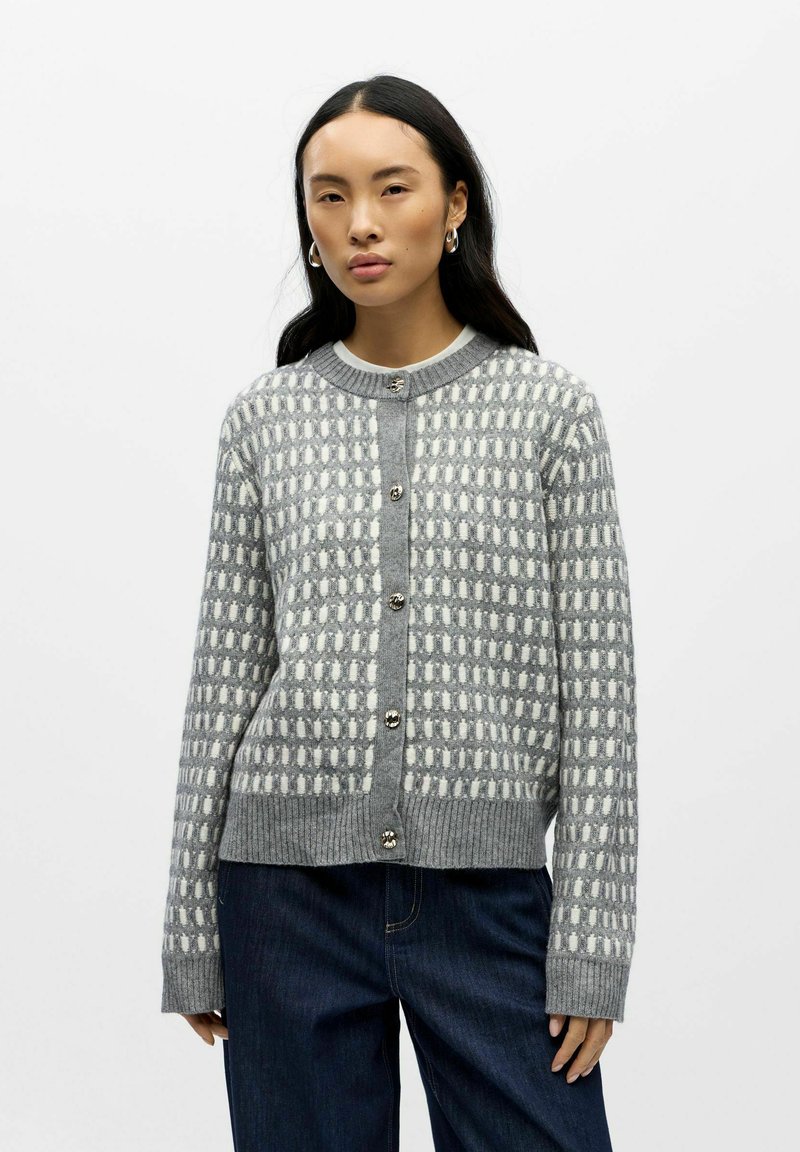 Szary, dziany kardigan o wzorzystej fakturze, z białymi kształtami geometrycznymi, okrągłym dekoltem i srebrnymi guzikami z przodu.