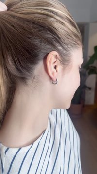 Silberner Creolenohring, runde Form, polierte Oberfläche, am linken Ohr getragen. Die Haare sind zurückgebunden, wodurch der Ohrring und der Halsbereich sichtbar sind.