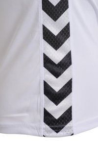Vitt sportkläder med svart och vitt chevronmönster på sidan. Tillverkat av slätt, andningsbart tyg med en strukturerad accent.