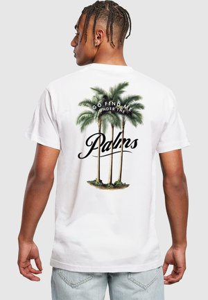 White cotton t-shirt featuring a palm tree graphic on the back with the text "Go find me under the Palms" in black script.