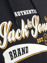 Hoodie nera con testo "AUTHENTIC Jack & Jones" in bianco e oro, caratterizzato da un grande font curvo e un'etichetta rettangolare "BRAND" in basso.