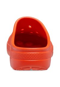 Sabot en caoutchouc rouge avec un dos arrondi, doté de trous de ventilation et de côtés texturés pour une meilleure prise. Intérieur lisse et semelle légèrement surélevée.