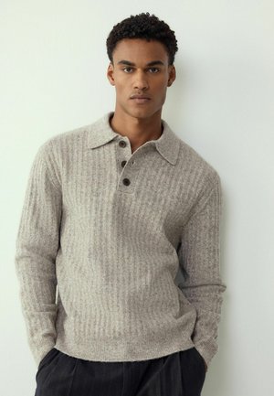 Light gray textured knit pullover with a collar, three brown buttons, and ribbed cuffs, worn over dark striped trousers.