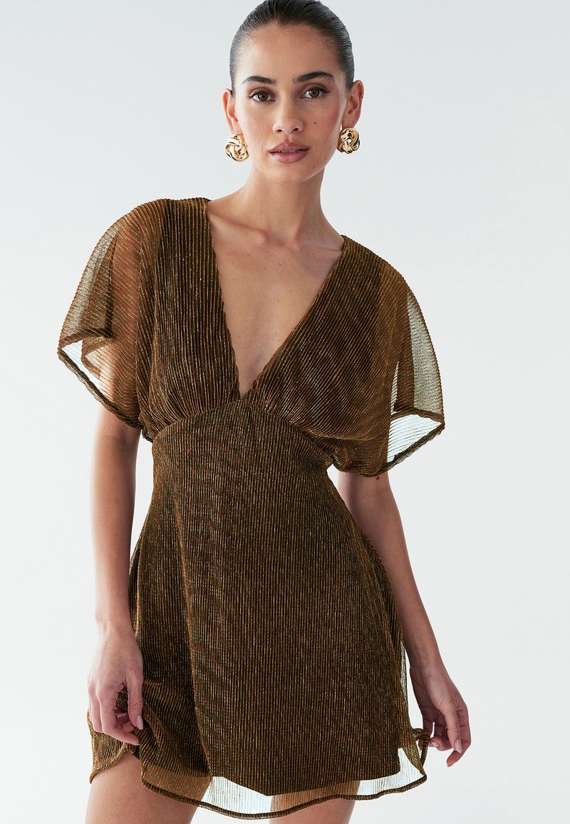Bronze plisseret kjole med dyb V-hals, gennemsigtige flutterærmer og en flydende silhuet, der har en tekstureret, glitrende overflade.