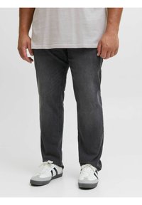Vaqueros gris oscuro con un corte relajado, confeccionados en tela de mezclilla. Combinados con zapatillas blancas y grises con rayas negras.