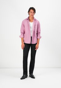 Light pink button-up shirt with rolled sleeves, paired with black pants and black leather shoes. The shirt features a subtle texture.
