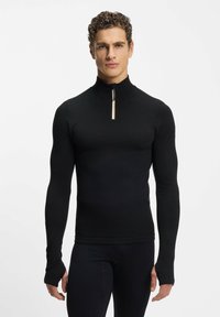 Czarny top z długim rękawem, z wysokim kołnierzem i ćwiartkowym zamkiem. Wykonany z gładkiej tkaniny, o dopasowanym kroju, z otworami na kciuki w mankietach.