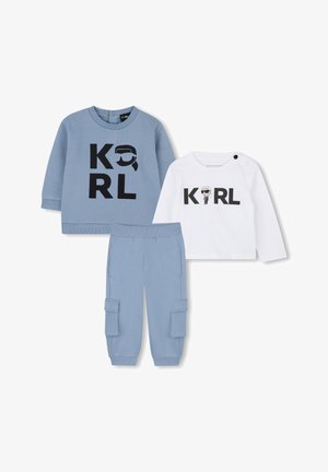 Twee overhemden met lange mouwen en blauwe cargobroeken. Het ene overhemd is lichtblauw met zwarte "KARL" tekst, het andere is wit met zwarte "KARL" tekst en een grafisch ontwerp.