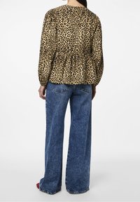 Blusa in stampa leopardata con vita stretta, maniche lunghe a palloncino e vestibilità comoda, abbinata a jeans a gamba larga in denim blu a vita alta.