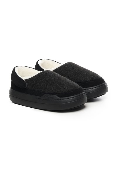 Zwarte instapslippers van vilt met een plush witte voering. Kenmerkt zich door een ronde neus en een dikke zwarte zool voor demping.