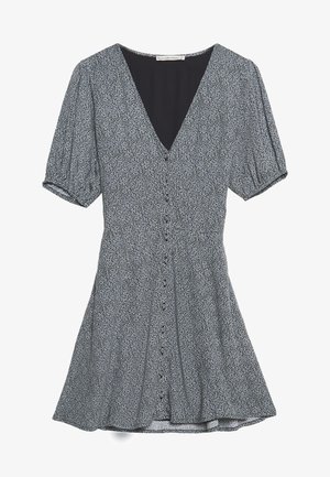 Czarna i biała sukienka w wzory z krótkimi bufkami, dekoltem w serek, zapinana na guziki i z rozkloszowaną spódnicą.