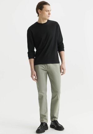 Czarna koszula z długim rękawem, jasnoszare spodnie, czarne buty, slim fit, gładki materiał, minimalny design, postawa stojąca z opuszczonymi rękami.