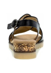 Zwarte leren sandaal met een gespsluiting, gevoerd voetbed en een zware hak met een geprofileerd dierenprint ontwerp.