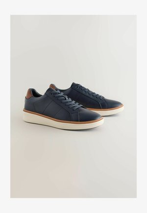 Granatowe skórzane sneakersy z jasnoniebieskimi sznurowadłami, teksturowaną białą gumową podeszwą i brązowymi skórzanymi akcentami na pięcie. Smukły design i przeszycia.