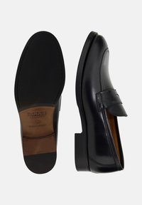 Černé kožené mokasíny s hladkým povrchem, kulatou špičkou a ozdobným proužkem přes nárt. Pevná gumová podrážka. Minimalistický design.