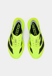 Lyse gule og svarte Adidas Adizero løpesko sett ovenfra, med lisser knyttet og logo synlig inni hver sko.