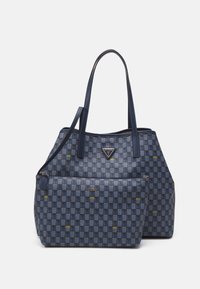 Niebieska torba typu tote w geometryczny wzór z skórzanymi uchwytami, z zamykaną na zamek przednią kieszenią i emblematem logo. Wykonana z wytrzymałego materiału.