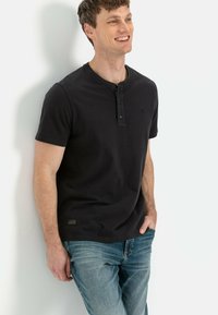 Dunkelgraues Kurzarm-Henley-Shirt mit einer Drei-Knopf-Leiste, strukturiertem Stoff, kombiniert mit hellblauen Denim-Jeans.